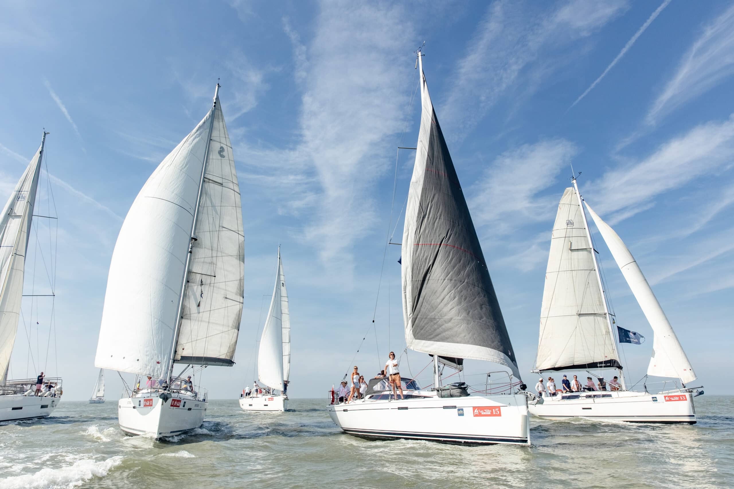 Zeilboten met witte zeilen onder een blauwe lucht