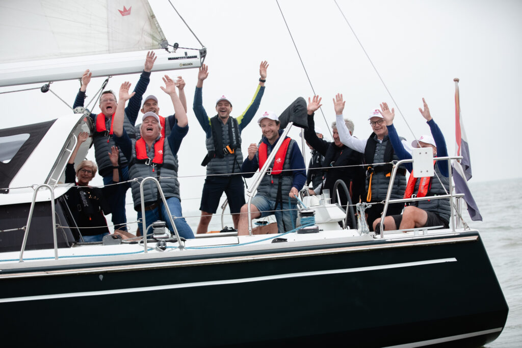 Een bedrijfsteam juicht aan boord van een zeilboot tijdens de regatta van 2024