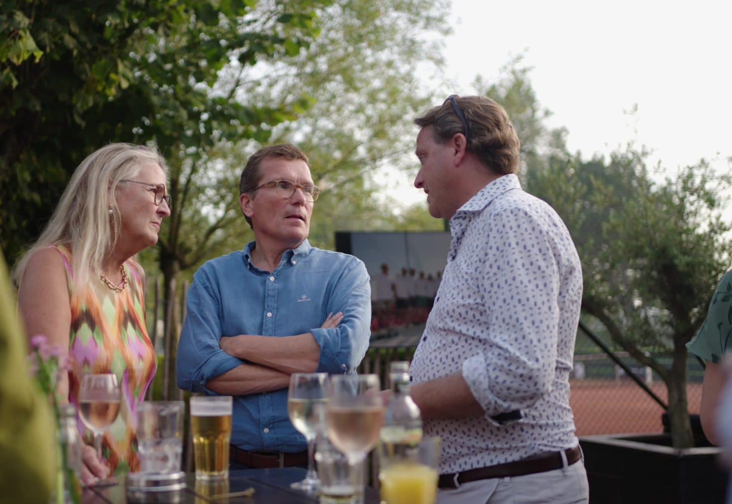 Gasten in gesprek aan een statafel op het terras